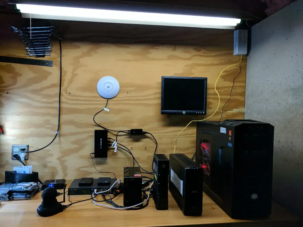 Expanded homelab workbench with several small devices, network gear, and visible cabling.