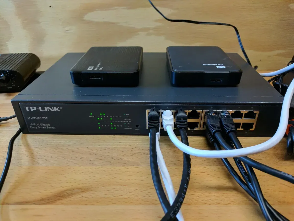 Close-up of a TP-Link network switch with two small computers resting on top.