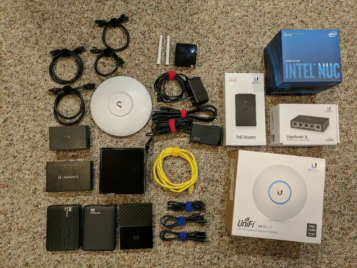 Intel NUC, Ubiquiti equipment, cables, and accessories laid out for the next homelab build.