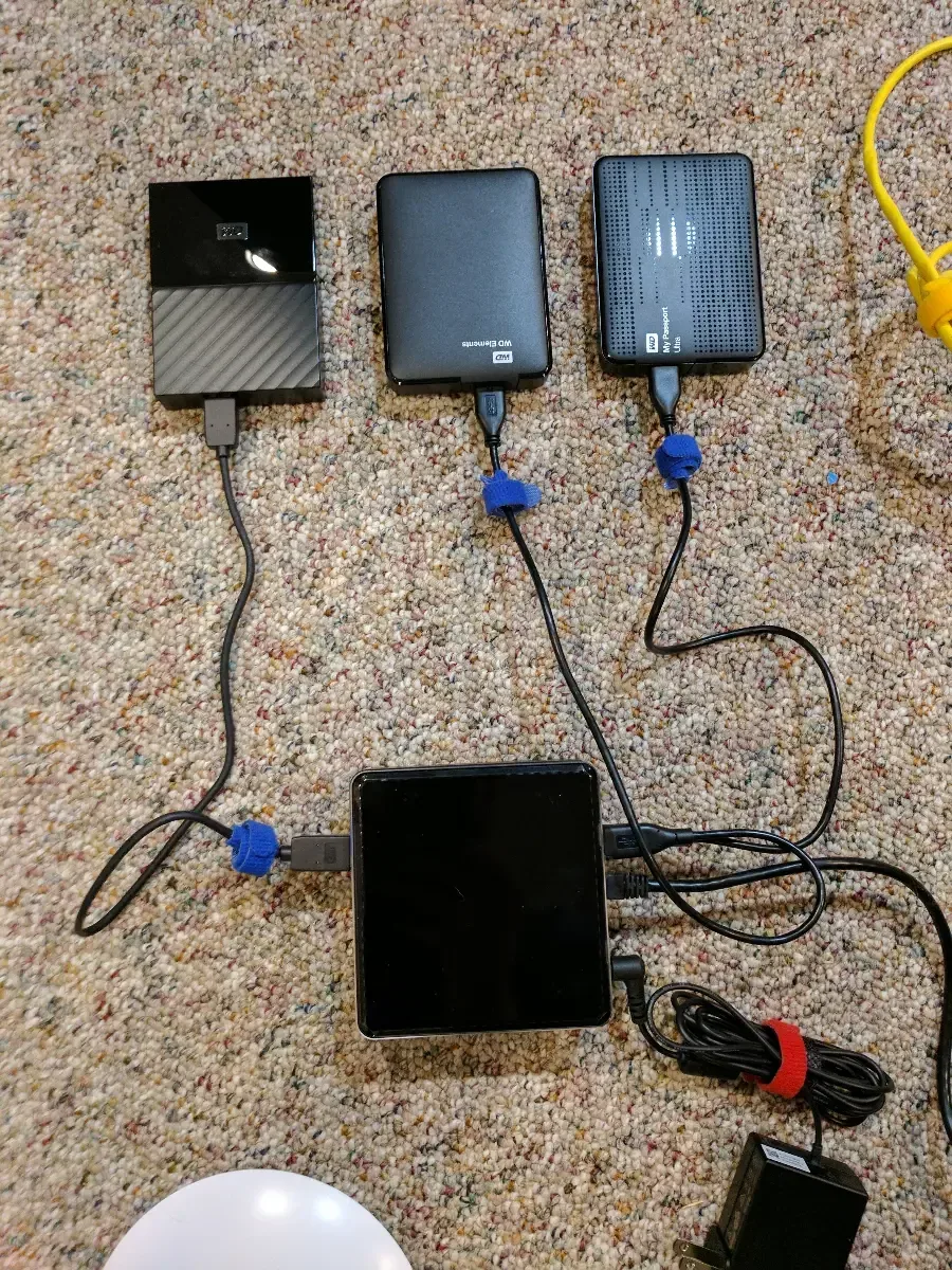 Small computers and external drives connected together on the floor during setup.
