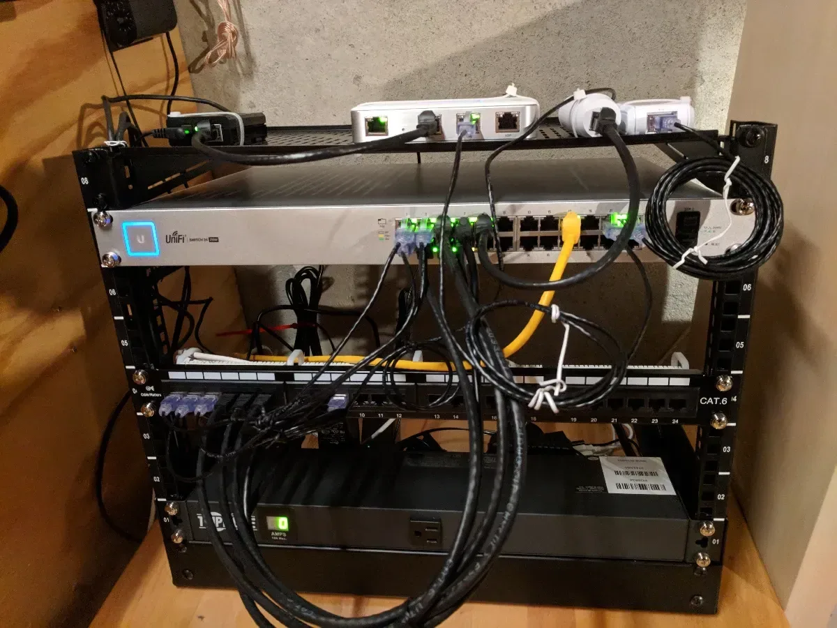 Front of the network rack with patch panels, a switch, cabling, and power distribution.