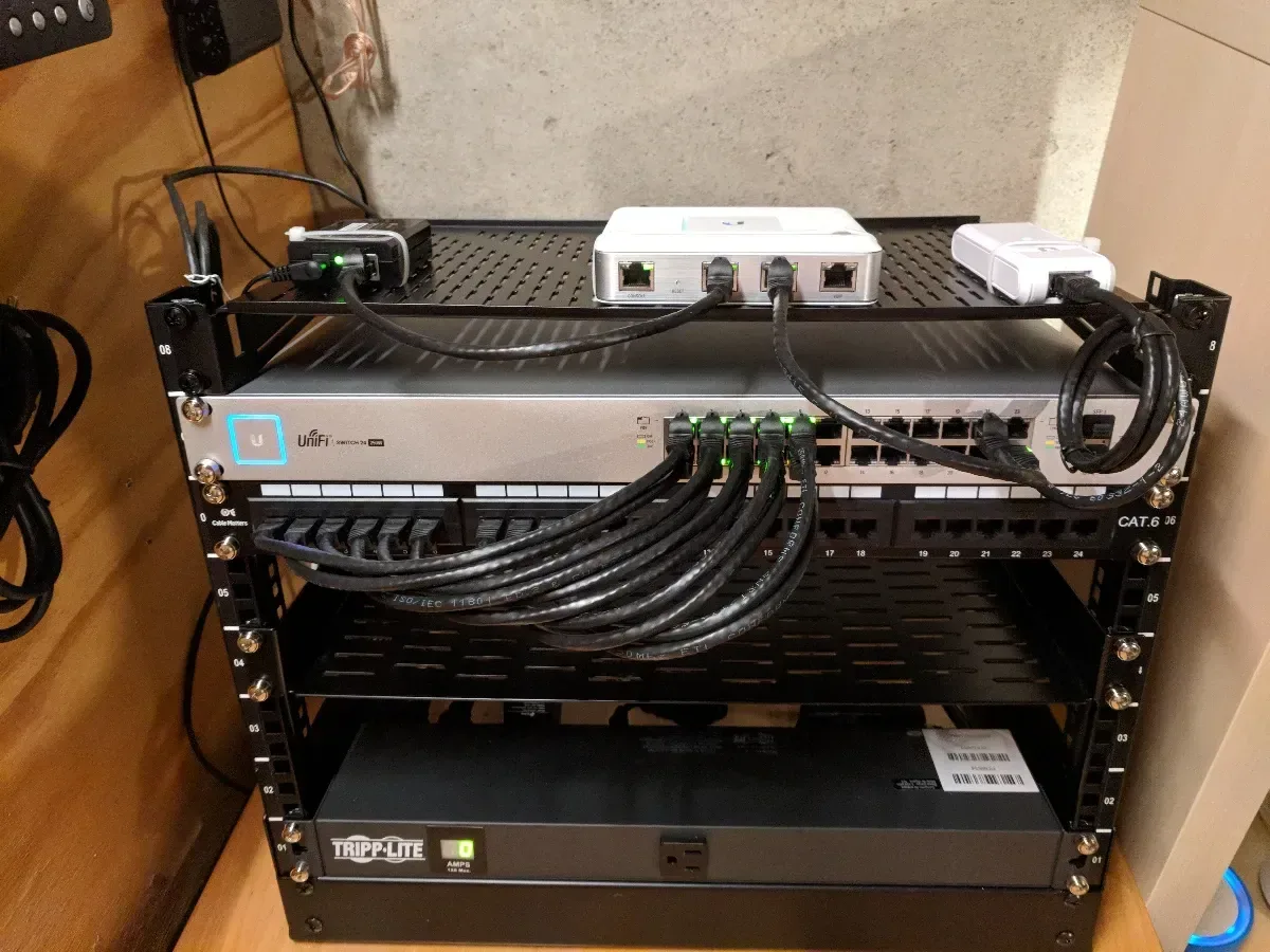 Lower section of the rack showing patch panels, network equipment, and a Tripp Lite UPS.