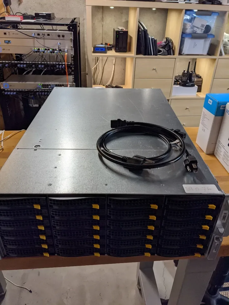 Rackmount storage chassis on a workbench with a coiled cable on top.