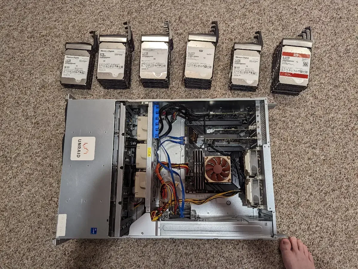 Open server chassis and six hard drives laid out on the floor for installation.