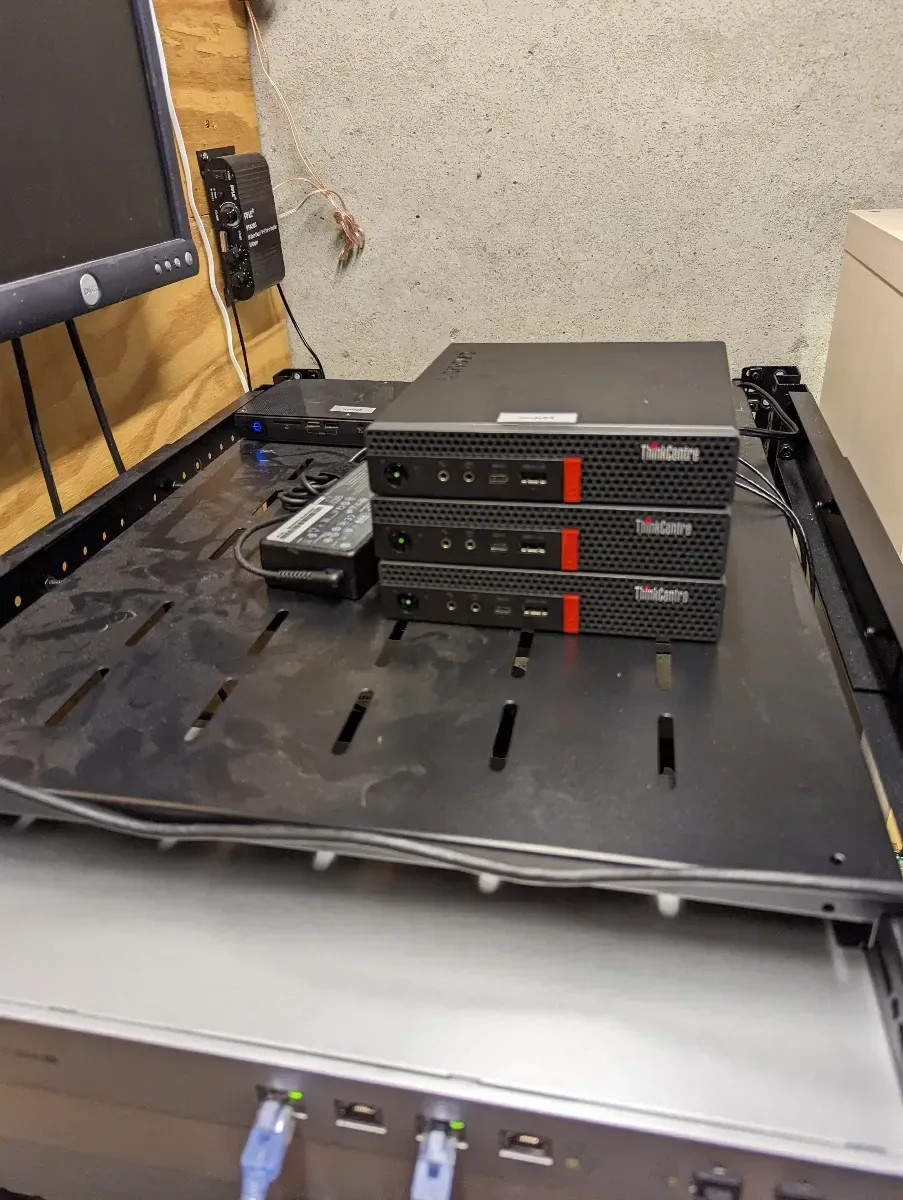 Four Lenovo Tiny computers arranged on a rack shelf.