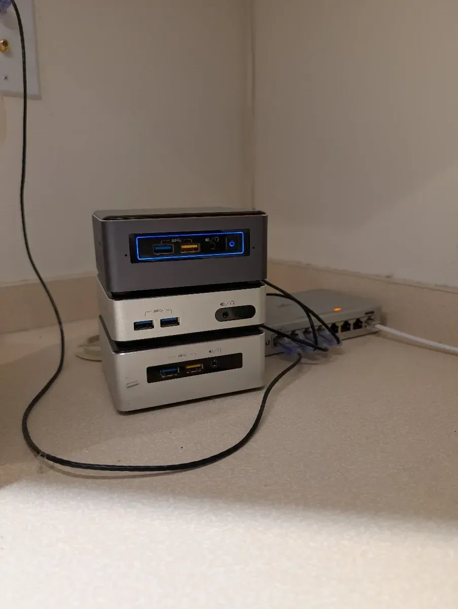 Two compact computers stacked on a shelf and connected for testing.