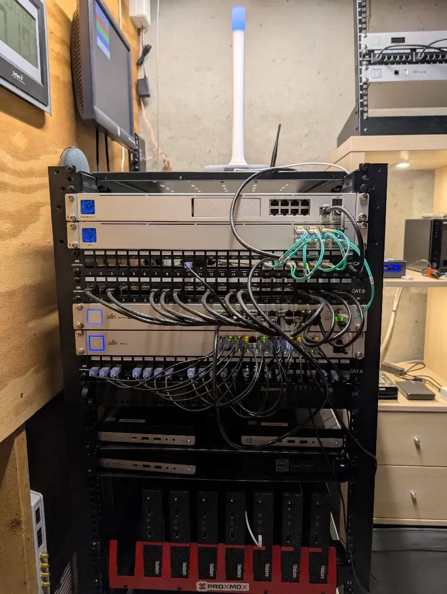 Full rack with switches, patch panels, a mini PC cluster, and storage hardware.